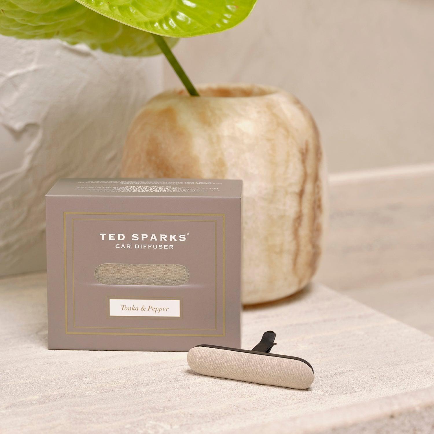 Elegant Ted Sparks car diffuser with Tonka & Pepper scent next to a decorative vase, enhancing your driving experience.